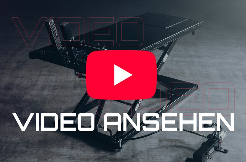 Schwarze Scherenhebebühne auf grauem Betonboden, rotes YouTube-Play-Symbol überlagert das Bild, großer weißer Schriftzug VIDEO ANSEHEN im Vordergrund