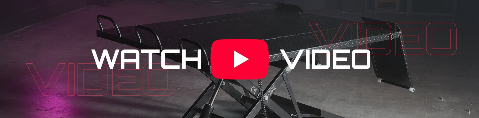 Raised black scissor-lift table with diamond-plate platform in a dim warehouse, overlaid by a large red YouTube play button and white text reading WATCH VIDEO, with magenta floor lighting