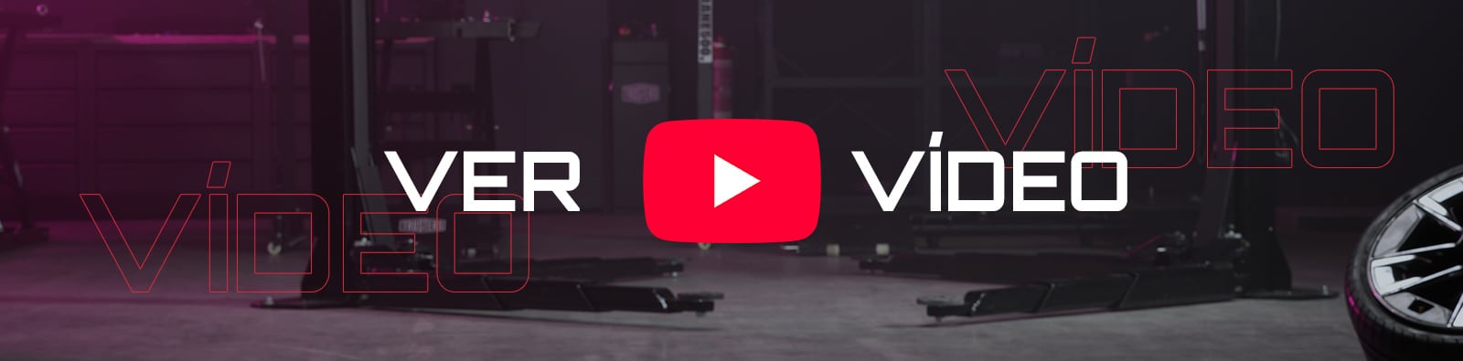 Botón de reproducción de YouTube rojo centrado con las palabras VER VÍDEO, sobre un taller automotriz oscuro con elevadores de coches en el suelo y una llanta visible a la derecha