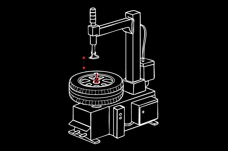 Máquina desmontadora de neumáticos: rueda montada en el plato central con cono central rojo, brazo articulado con herramienta encima y flechas rojas que indican movimiento vertical; ilustración lineal blanca con acentos rojos sobre fondo negro