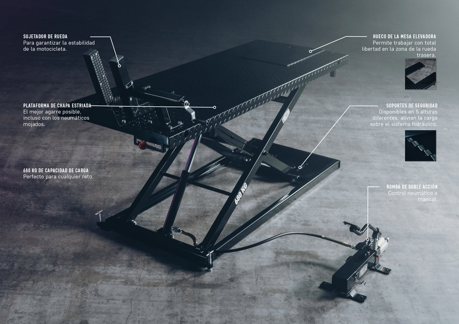 Mesa elevadora para motocicletas negra tipo tijera con plataforma de chapa estriada, sujetador de rueda, hueco trasero, capacidad 680 kg, soportes de seguridad y bomba hidráulica de doble acción conectada por manguera, sobre suelo de hormigón.