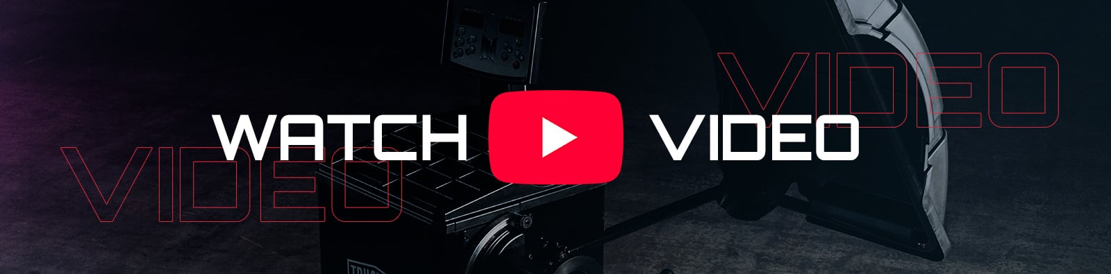 Dark industrial studio scene with large white text WATCH and VIDEO flanking a red YouTube play button overlaying camera equipment and a studio light on a concrete floor