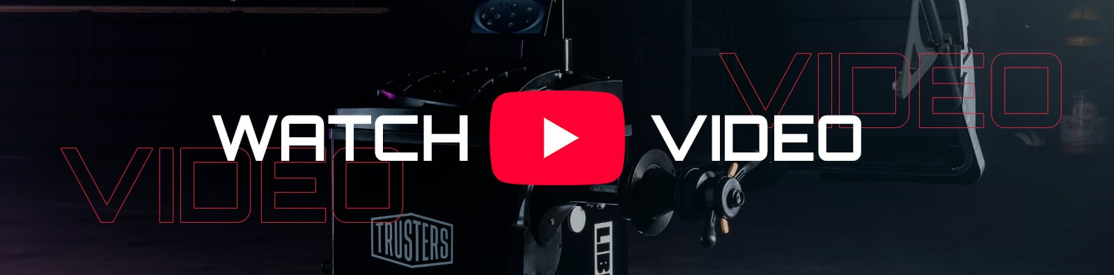 Dark studio scene with a film camera and large red YouTube play icon centered, bold white text WATCH and VIDEO on either side, faint outlined VIDEO text in the background