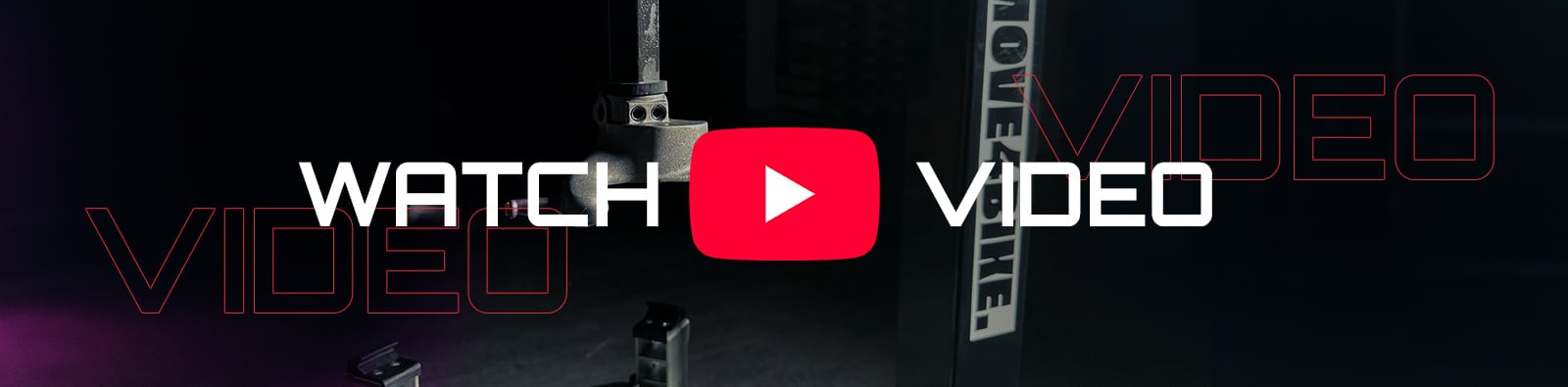 White capital text WATCH and VIDEO separated by a red YouTube play button over a dark studio scene with camera rig, stands and faint red outlined VIDEO lettering on left and right