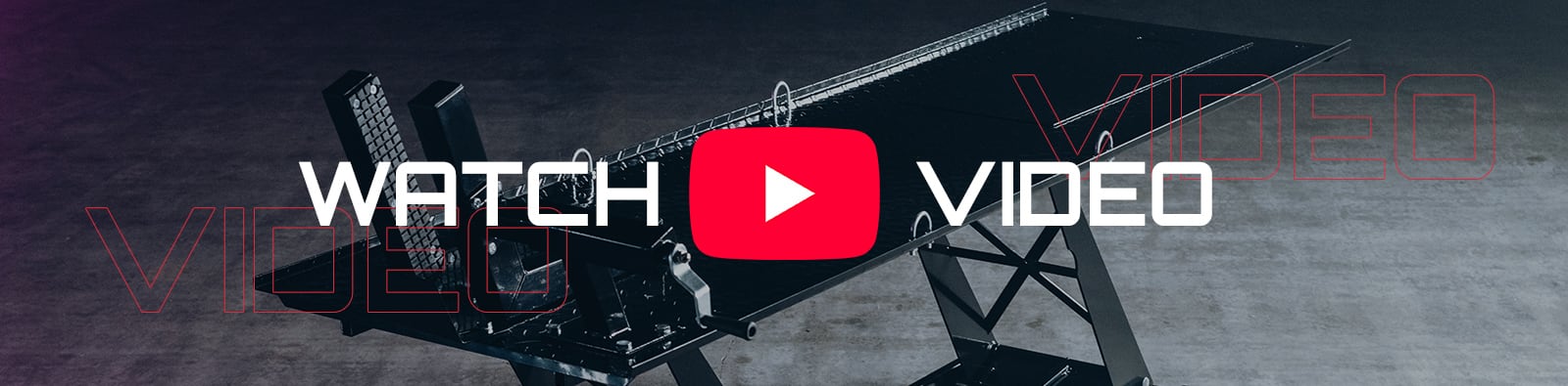 Black adjustable workout bench on a concrete studio floor with a large red YouTube play button centered and bold white text reading WATCH and VIDEO overlaid, faint red outlined VIDEO repeated in the background