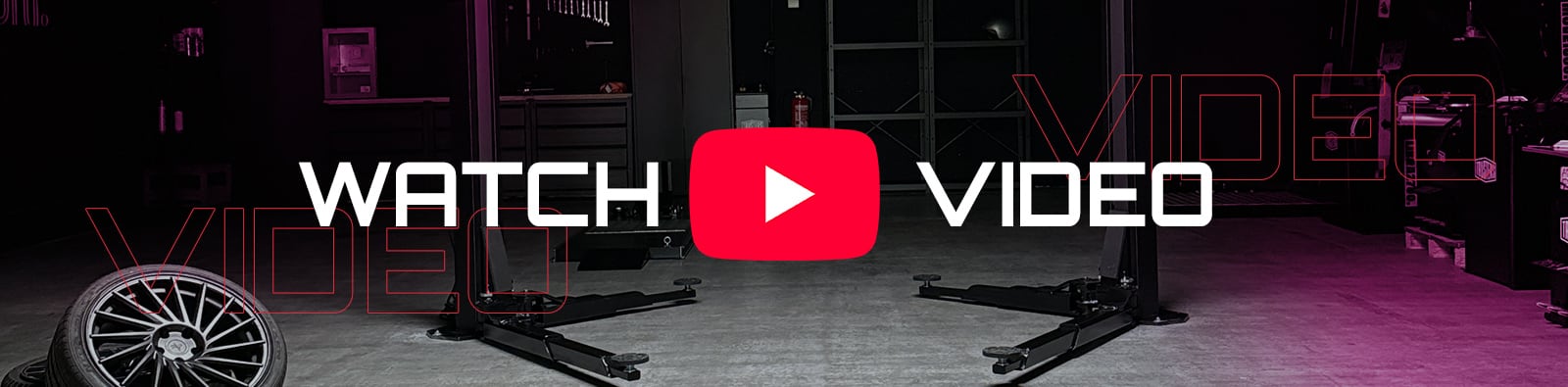 Garage interior with two-post vehicle lift, spare alloy wheel on concrete floor, purple lighting, overlaid large red YouTube play button and bold text WATCH VIDEO