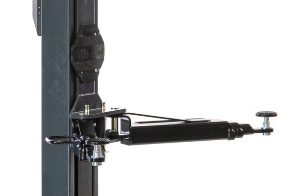 Black adjustable metal mounting arm attached to a vertical square column, showing rectangular mounting plate, swivel joint, threaded adjustment screw with knurled knob and quick-release securing strap