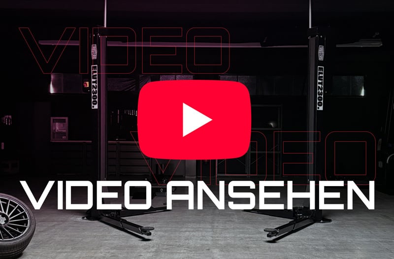 Dunkle Autowerkstatt mit Zweisäulen-Hebebühne, großes rotes YouTube-Play-Symbol in der Bildmitte und weißer Schriftzug VIDEO ANSEHEN im Vordergrund
