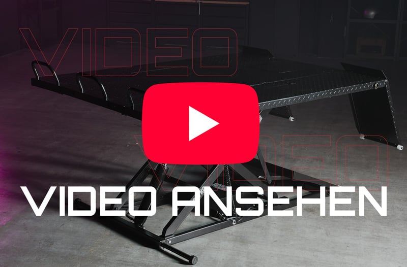 Scherentisch/Hebebühne auf Betonboden in dunkler Halle, großes rotes YouTube-Play-Symbol in der Bildmitte und weißer Schriftzug VIDEO ANSEHEN