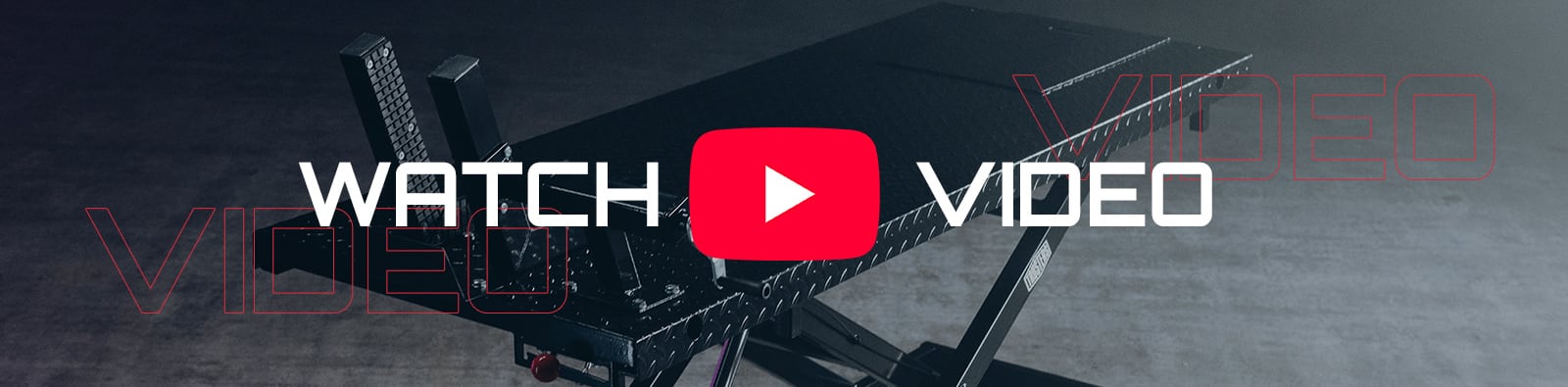Black scissor-style motorcycle lift table in a dim garage on a concrete floor, overlaid with large white text WATCH and VIDEO and a centered red YouTube play button icon